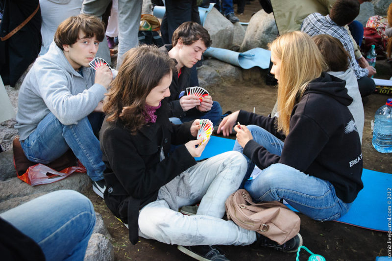 four young people sitting down and playing uno