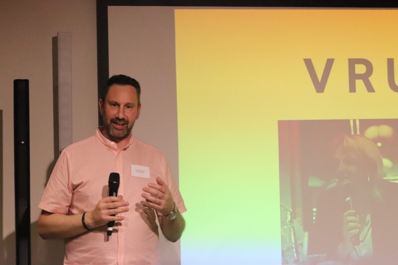 Rocket Science Director Michael Theordorou speaking into a microphone in front of a projector screen