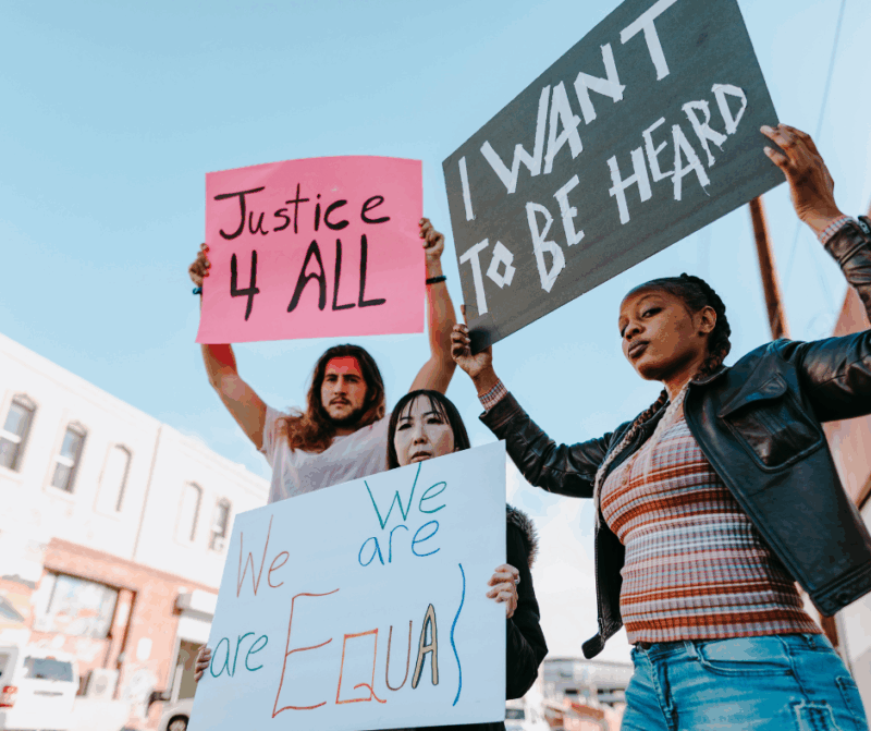 Three people holding placards for justice, equality